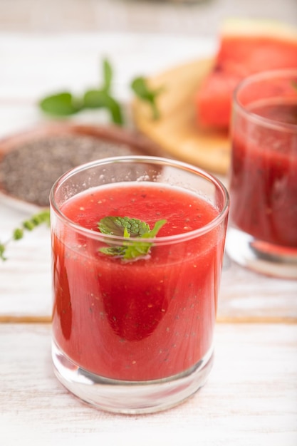 Watermelon juice with chia seeds and mint in glass on a white wooden background with linen textile. Healthy drink concept. Side view,  close up, selective focus.