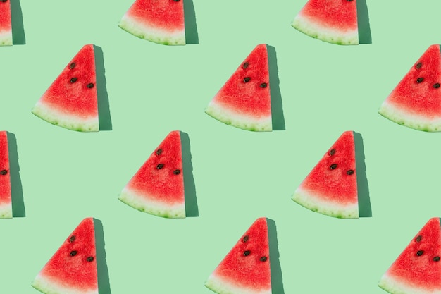 Watermelon pattern made of sliced watermelon on mint green background.