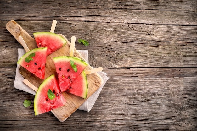 Watermelon pieces on sticks on wooden background. Top view. Copy space.