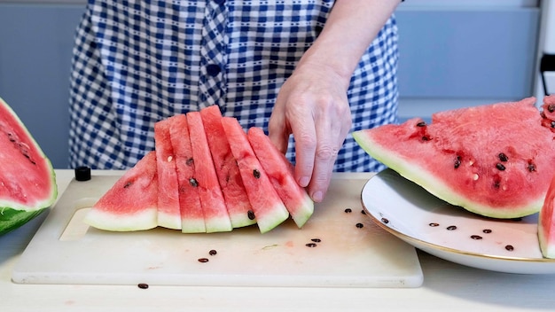 Watermelon season Female hands serving triangular slices of ripe watermelon