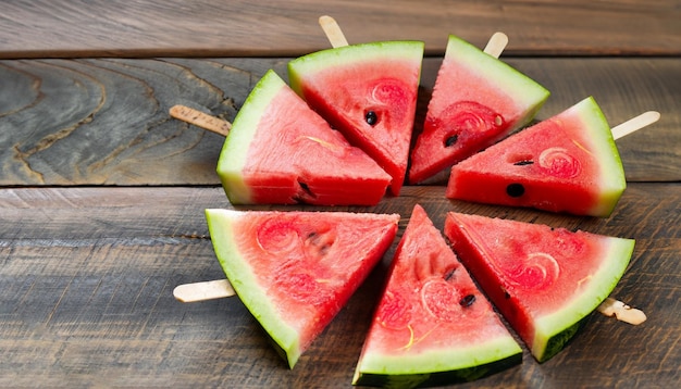 Watermelon slices on a stick on a wooden table