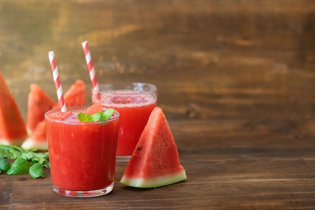 Watermelon smoothie in jars with fresh watermelon slices on gray wooden background. Copy Space.