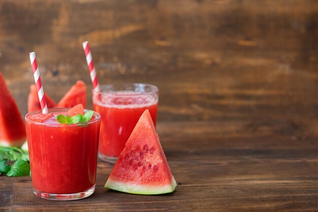 Watermelon smoothie in jars with fresh watermelon slices on wooden background. Copy Space