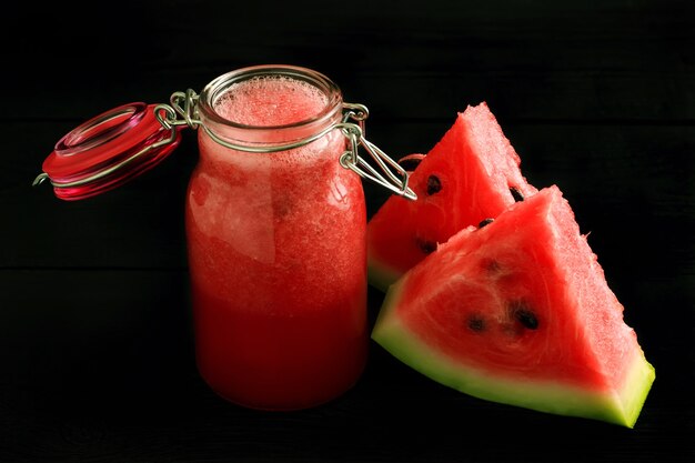 Watermelon smoothies in a jar and two slices of watermelon