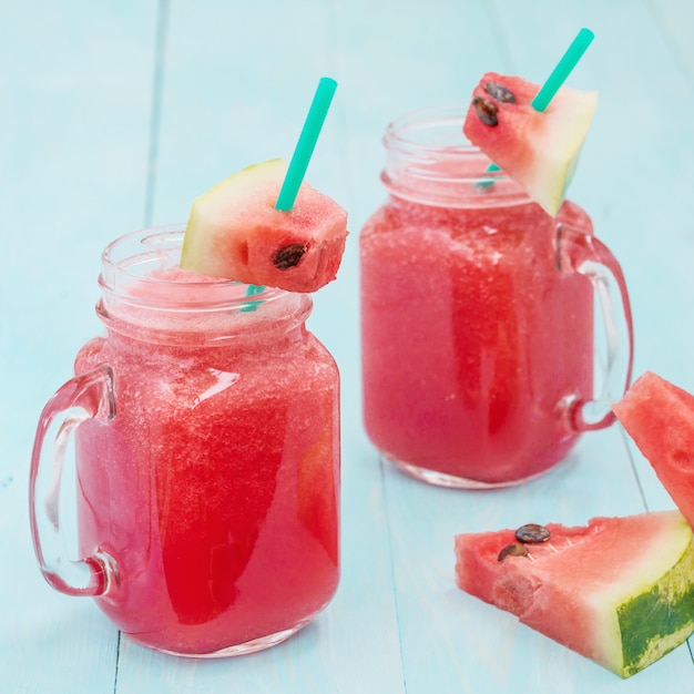 Watermelon smothie and slices on blue background