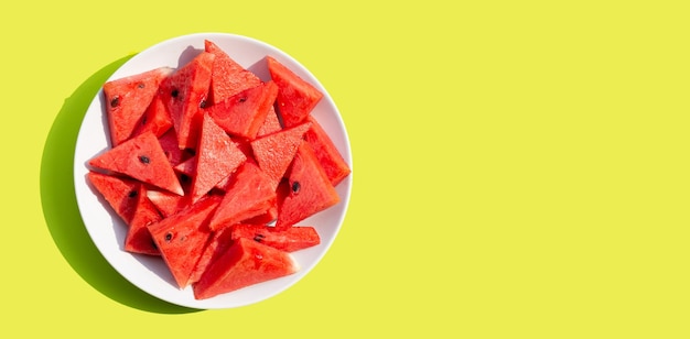 Watermelon in white plate on green background.