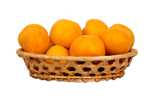 Wattled basket with ripe yellow apricots isolated on white background