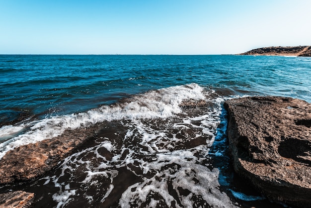 The wave breaks on the rock