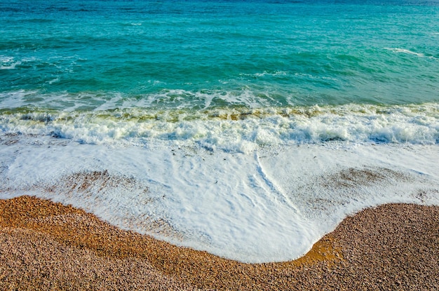 A wave runs over a pebble beach.