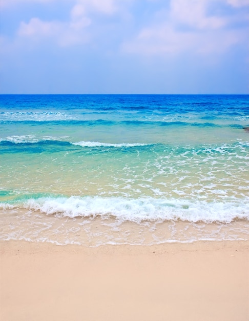 Wave of the sea on the sand beach against clody sky