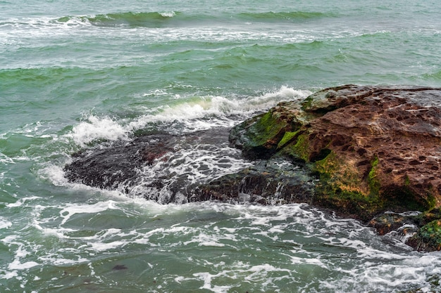 Wave splashing at the rocks, freshness on beach