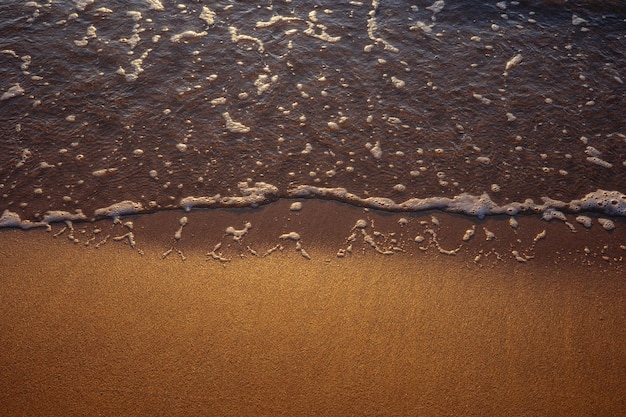 A wave washes onto the beach with the word sea on it.