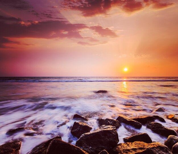 Waves and rocks on beach of sunset