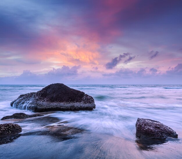 Waves and rocks on beach of sunset