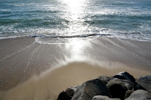 Waves roll onto the sandy sea beach Stone blocks lie on the beachPicturesque sea summer landscape