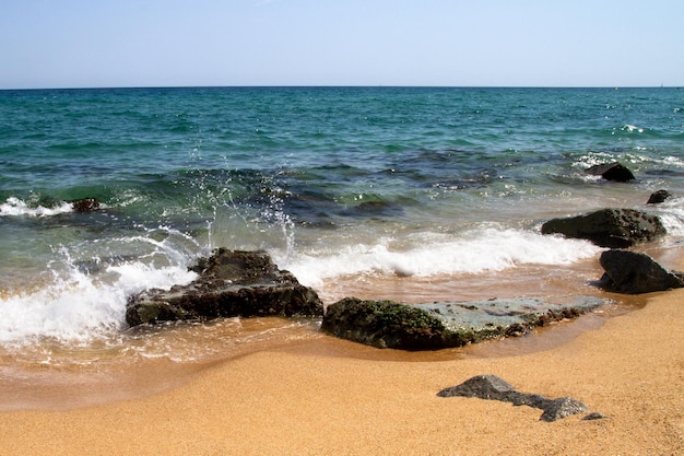 Waves, sea, beach, clear water. Stones under water.