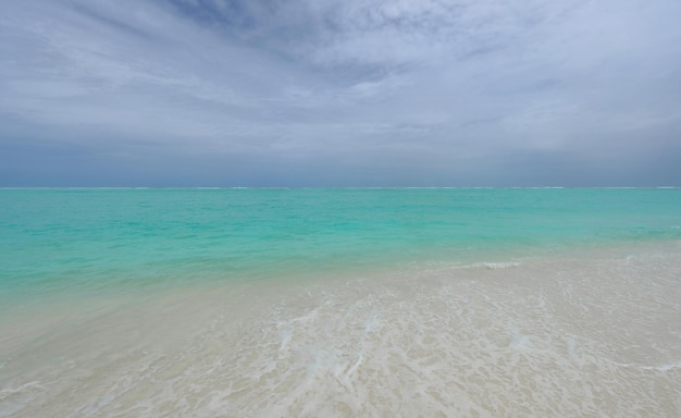 waves on turquoise water in the ocean and sky with clouds