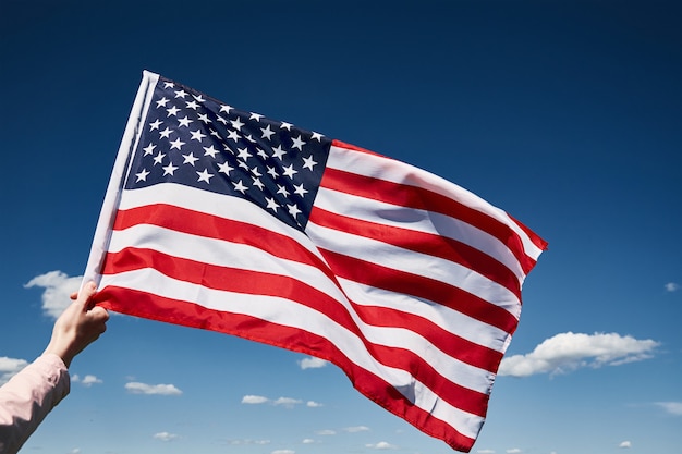 Waving american flag outdoors hand holds usa national flag against blue cloudy sky th july independence day