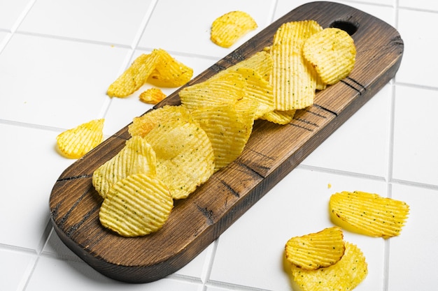 Wavy Original Potato Chips on white ceramic squared tile table background