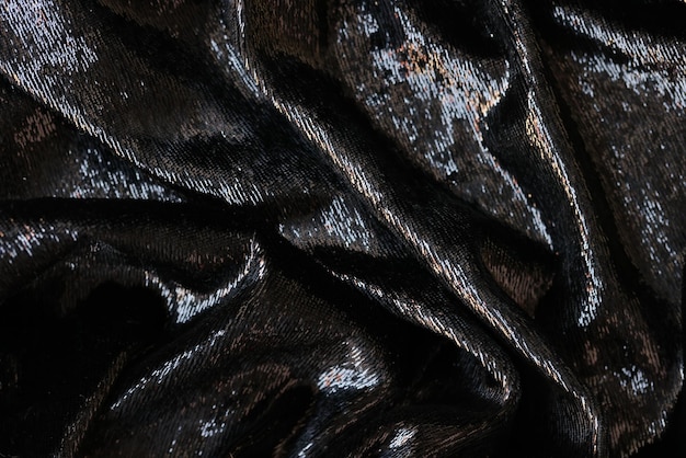 Wavy shining black fabric as background close up of black textile