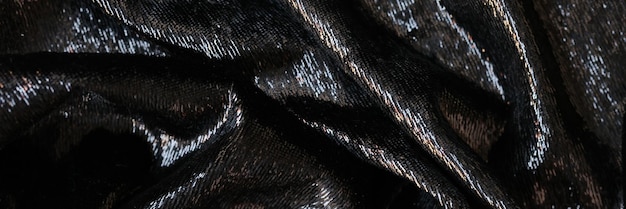 Wavy shining black fabric as background close up of black textile