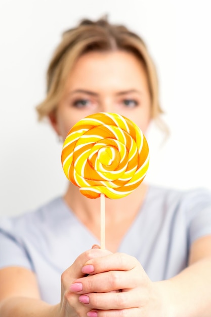 Waxing depilation concept The beautician is wearing a medical coat holding a sugar lollipop on white background