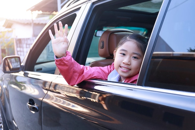 On the way to school, the little girl stretched out his hand from the car window, laughing and smiling.