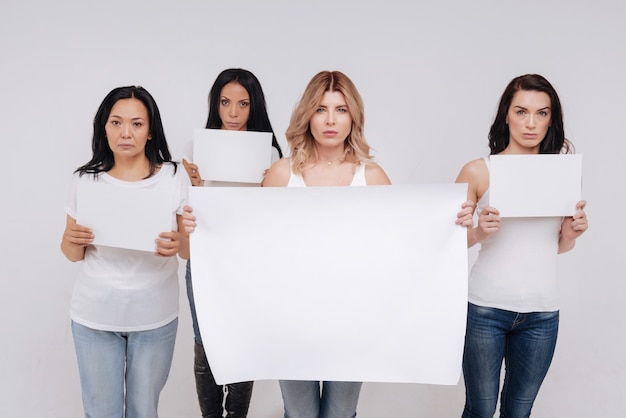 We are not silent. Magnificent fearless young ladies pretending marching against some social injustices while holding posters and standing isolated