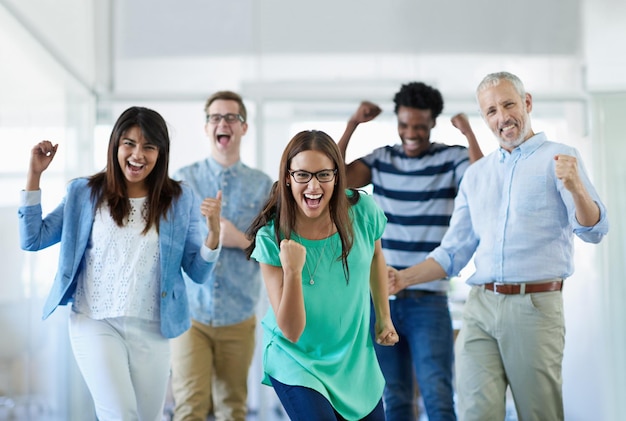 We did it Cropped portrait of a group of businesspeople cheering in an office