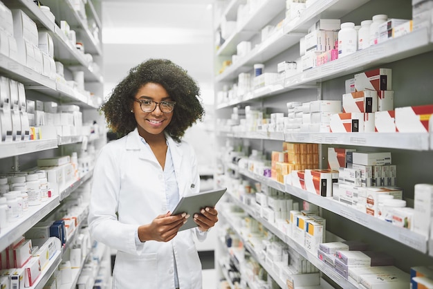 We have all the medication anybody would ever need Portrait of a cheerful young female pharmacist standing with a digital tablet while looking at the camera in a pharmacy