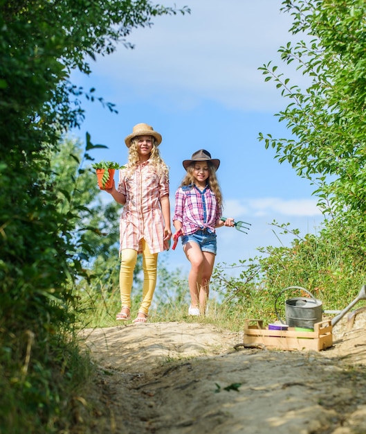 We love flowers small girls farmer in village ecology and environmental protection children hold gardening tools earth day summer family farm farming and agriculture spring country side