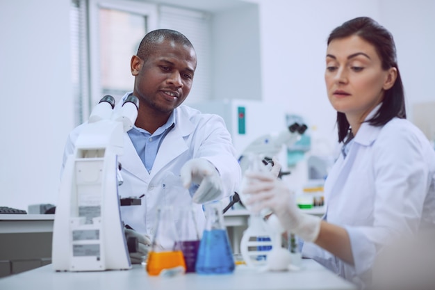 We love science. Determined experienced researcher conducting a test and his colleague helping him