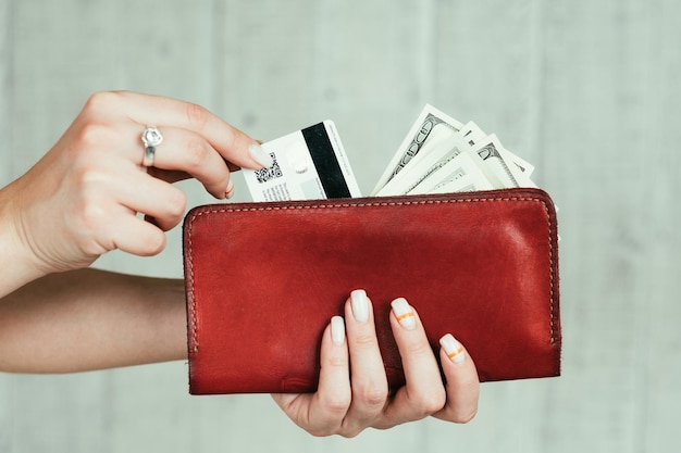 Wealth and finances money earning cash and credit cards welfare and income concept woman hands holding a red leather wallet full of currency