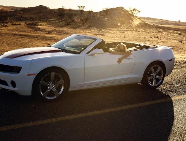 Wealthy woman during journey in desert by convertible car