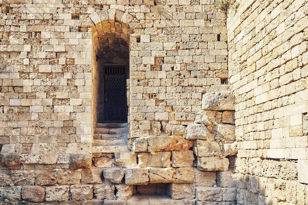 Weathered ancient Rhodes fortress brick and stone wall with empty arch doorway