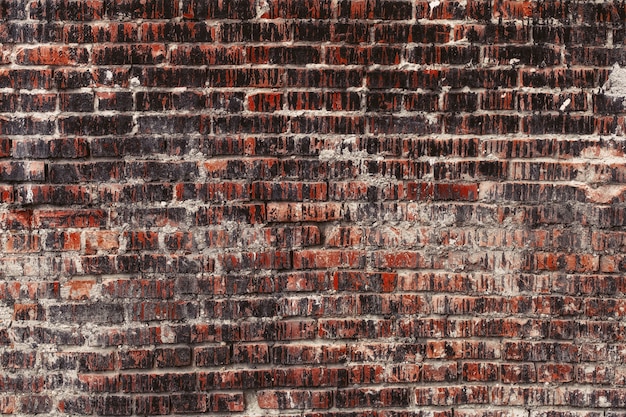 Weathered stained old dark brick wall, texture grunge background