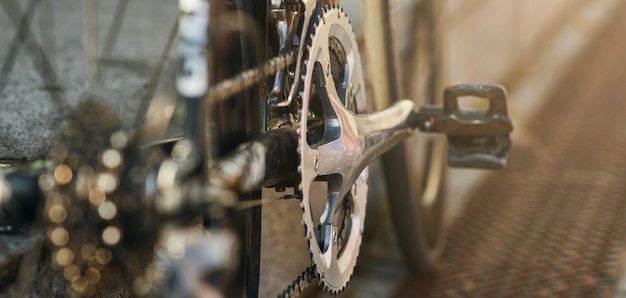 Website header of detailed view of bicycle mechanisms sprocket pedal and chain on a mountain