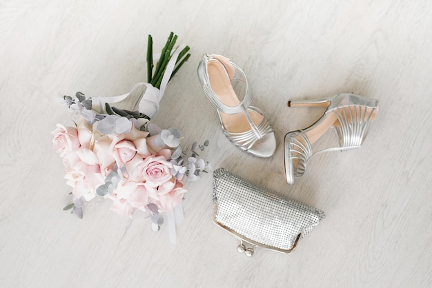 Wedding accessories for the bride a bouquet of pink roses bags and shoes on the background