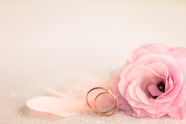 Wedding Background with gold Rings gentle flower and light pink feather