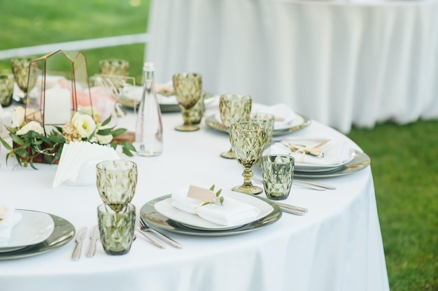 Wedding Banquet The chairs and round table for guests served with cutlery greenery flowers and crockery and covered with a white tablecloth olive color