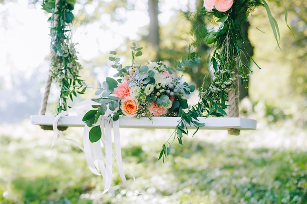 Wedding bouquet of beige and pink roses outdoors on the decorated swing