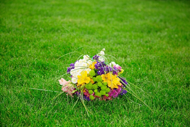 Wedding bouquet of colorful flowers lying on a green lawn