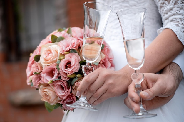 Wedding bouquet in the hands of the bride and groom at the ceremony glasses of champagne