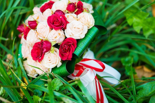 Wedding bouquet of red and white roses lying on grass