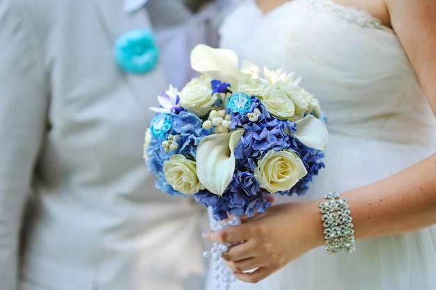 Wedding bouquet of white and blue roses flowers in bride hands