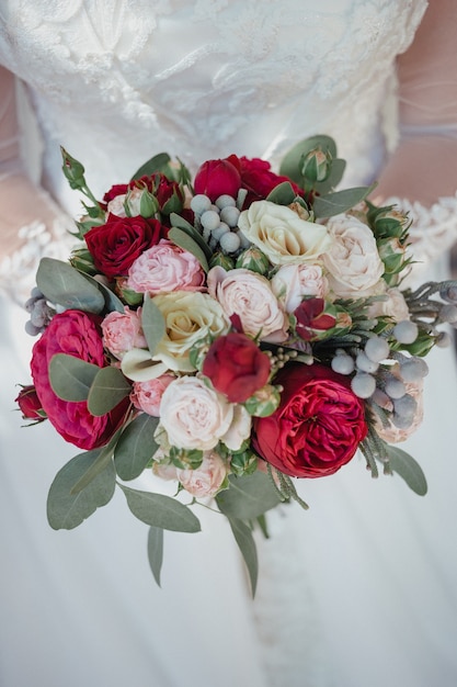 Wedding bouquet with roses in hands of the bride