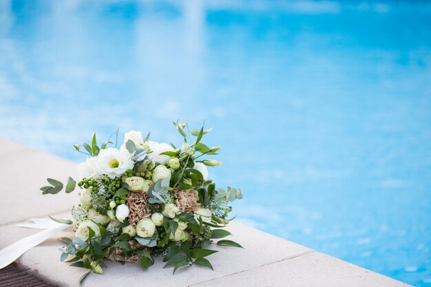 Wedding bridal bouquet on pool border close-up.