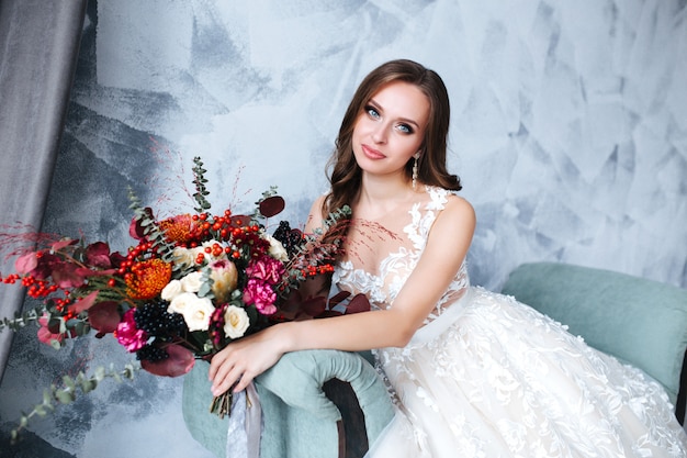 Wedding. Bride in beautiful dress sitting on sofa indoors