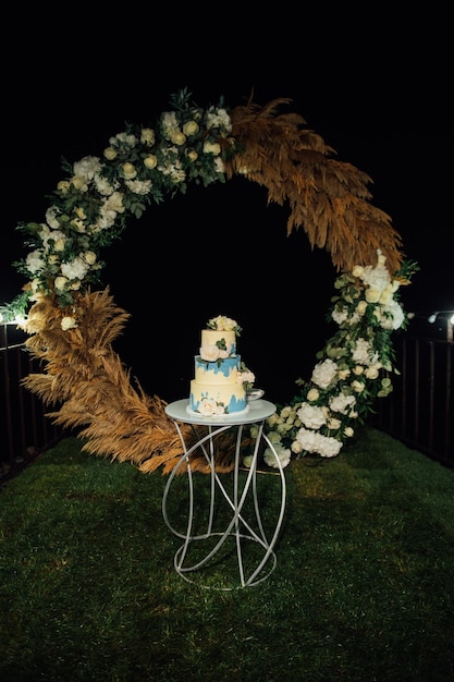 Wedding cake at the wedding in the evening on the background of the arch