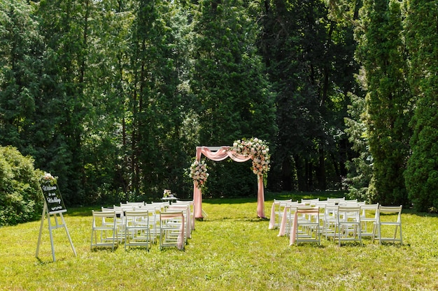 Wedding ceremony decorations chairs mirror pointer and a lot of flowers in white and pink colors